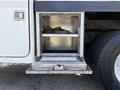 A metal storage compartment with two shelves is open on the side of a 2006 International 7500 truck showing its interior layout and contents