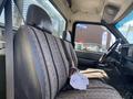 Interior view of a 1996 GMC Top Kick featuring a bench seat with a striped pattern and a coffee cup on the seat
