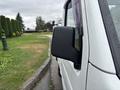 A side view of a white 2010 Suzuki Carry with raindrops on the mirror and body