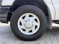 A close-up of a 2008 Ford Econoline's tire and wheel displaying silver alloy spokes and a rugged tread pattern