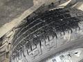 Close-up of a rugged tire of a 2022 GMC Savana showing detailed tread pattern with dirt and debris visible on the surface