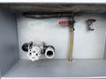 A metallic compartment featuring a white valve with a wheel handle a brass pipe with a red valve and a silver pipe connected to a wire mesh filter