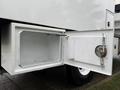 A white storage compartment door of a 2020 International MV607 truck is open revealing an empty interior space with a hanging latch mechanism