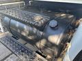 A black fuel tank mounted on a 2008 International 4400 truck with a textured surface and a circular cap on top