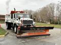 A white 2012 International 7400 truck with a large front snow plow attached labeled "PLOW KING" in black lettering