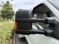 Close-up of the side mirror of a 2008 Ford F-550 showing its black casing and integrated orange turn signal light