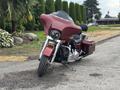 A 2009 Harley-Davidson Road King motorcycle in red with a large windshield and saddlebags parked on a street