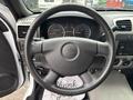 Steering wheel of a 2011 Chevrolet Colorado with dashboard gauges and audio controls visible in the background