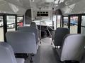 Interior view of a 2013 Chevrolet Express showing gray seats, aisle, and dashboard with large windows on each side