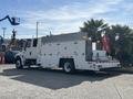 A 2006 International 4300 truck with a white body is equipped with a utility bed and hydraulic lift at the rear