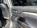 A 2018 Toyota Highlander door interior showing the handle window controls and armrest with a dark leather finish and metallic accents