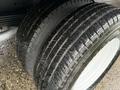Close-up of two large, well-treaded tires mounted on a white wheel showcasing a rugged tread pattern and wet surface
