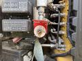 A close-up of a 2022 Caterpillar 306 control panel featuring various switches and circuit breakers with a red rotary switch prominently displayed