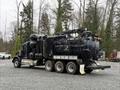 A 2018 Kenworth T800 truck equipped with a large black tank and multiple hoses mounted on its back
