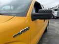 A yellow 2014 Ford F-150 with a chrome badge displaying the model name on the side and a side mirror visible in the foreground