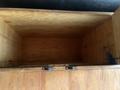 Interior view of a wooden storage box with a smooth, unfinished surface and metal hinges on the front