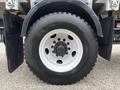 A close-up of a black tire with a white rim featuring multiple bolt holes designed for a 2017 Autocar Xpert vehicle