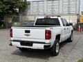 A 2018 Chevrolet Silverado 1500 in white with a black bed cover and chrome accents parked with its rear facing the viewer