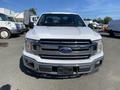 Front view of a white 2018 Ford F-150 with a chrome grille and headlights visible