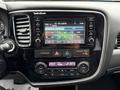The dashboard of a 2016 Mitsubishi Outlander featuring a radio display with multiple station presets and climate control knobs for adjusting temperature and fan settings