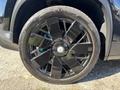 A close-up of a black alloy wheel on a 2023 Fisker Ocean showcasing a sleek eight-spoke design and blue brake calipers