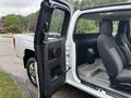 A 2011 Chevrolet Colorado with the driver's door open revealing the interior and rear seating area featuring gray fabric seats and a minimalist design