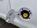 A close-up of the fuel filler cap of a 2015 GMC Sierra 1500 with a yellow fuel funnel inside the opening