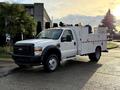 A 2010 Ford F-550 work truck in white with a utility bed and equipment mounted on top