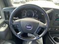 The interior view of a 2022 GMC Savana showing a steering wheel with the GMC logo and dashboard gauges including speedometer and fuel indicators