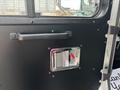A close-up of a black door panel from a 2020 Freightliner MT45 featuring a chrome handle and a rectangular compartment with a red lever.