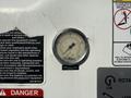 A pressure gauge labeled Altec indicating a measurement on a white dial with a needle pointing slightly above the zero mark