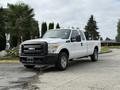 A white 2011 Ford F-250 Super Duty pickup truck with a standard cab and black grille parked on a concrete surface