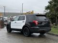 A 2019 Ford Explorer with a black and white exterior parked on a wet surface showcasing its rear and side view