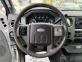 Steering wheel of a 2012 Ford F-550 with buttons for audio and cruise control alongside various gauges on the dashboard