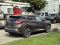 A 2016 Nissan Murano in a metallic brown color with sleek lines and distinctive rear taillights parked on a grassy area