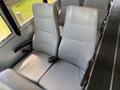 Interior view of two grey vinyl bus seats with vertical stitching on the seatbacks and adjustable armrests