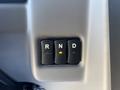 Close-up of a gear shift panel featuring three buttons labeled R N and D with an indicator light illuminated in yellow