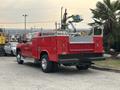 A red 2015 Chevrolet Silverado 3500HD with a flatbed and tool racks is parked with its rear view visible