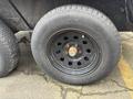 A close-up of a black steel wheel with a central hub and six lug nuts mounted on a tire labeled Steel Belted Radial and marked with the brand name Coodyear