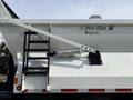 A close-up view of a white 2013 International WorkStar truck featuring a hydraulic lift system and a black metal ladder leading to the truck bed