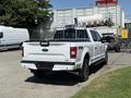 A white 2018 Ford F-150 pickup truck parked with a bed liner and a metal rack visible in the bed