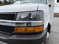 A 2013 Chevrolet Express van showcasing its front grille headlights and bumper with a wet surface reflecting light