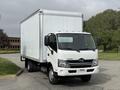 A 2018 Hino 195 truck with a white box cargo area and a black grille parked on the road