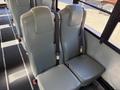 A pair of grey bus seats with seatbelts installed in a school bus interior