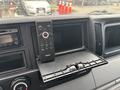 Dash of a 2015 Mitsubishi Fuso FE160 showing a Clarion stereo system and a remote control sitting on a foldable shelf