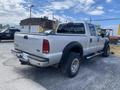 A silver 2007 Ford F-350 SD pickup truck with a crew cab and black wheel flares parked on gravel