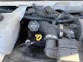 A close-up of the engine compartment of a 2013 Chevrolet Express showing the throttle body with a yellow dipstick and wiring harnesses attached