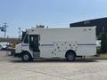 A white 2011 Workhorse W62 delivery truck with a blue stripe and side compartments is parked, showing its profile and distinct boxy shape