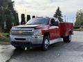 A red 2013 Chevrolet Silverado 3500HD pickup truck with a silver grille and a service bed on the back parked in a lot