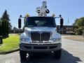 A white 2010 International 4300 truck with a bucket lift on top and multiple safety lights mounted on the cab